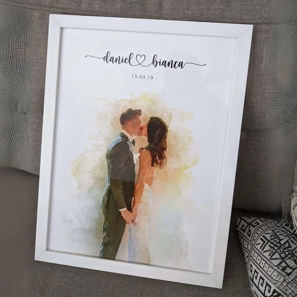 Watercolor-style portrait of a couple kissing, in a white frame leaning on a sofa, with their names and a date above
