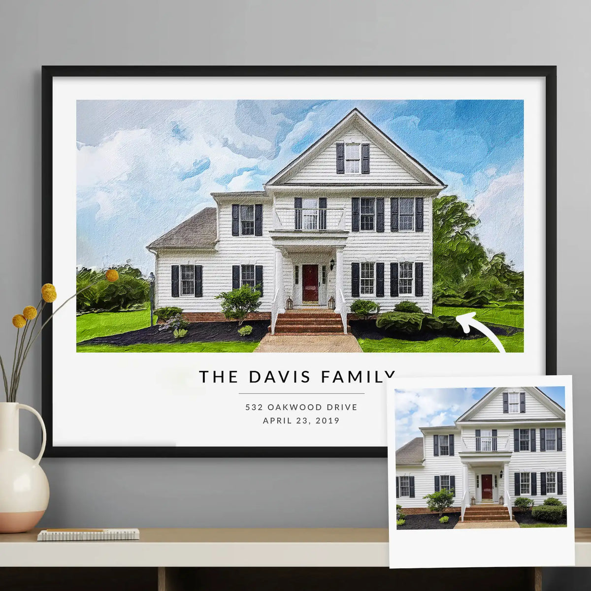 Oil-style portrait of a large white house, 'The Davis Family', framed in black, beside the photo it was made from