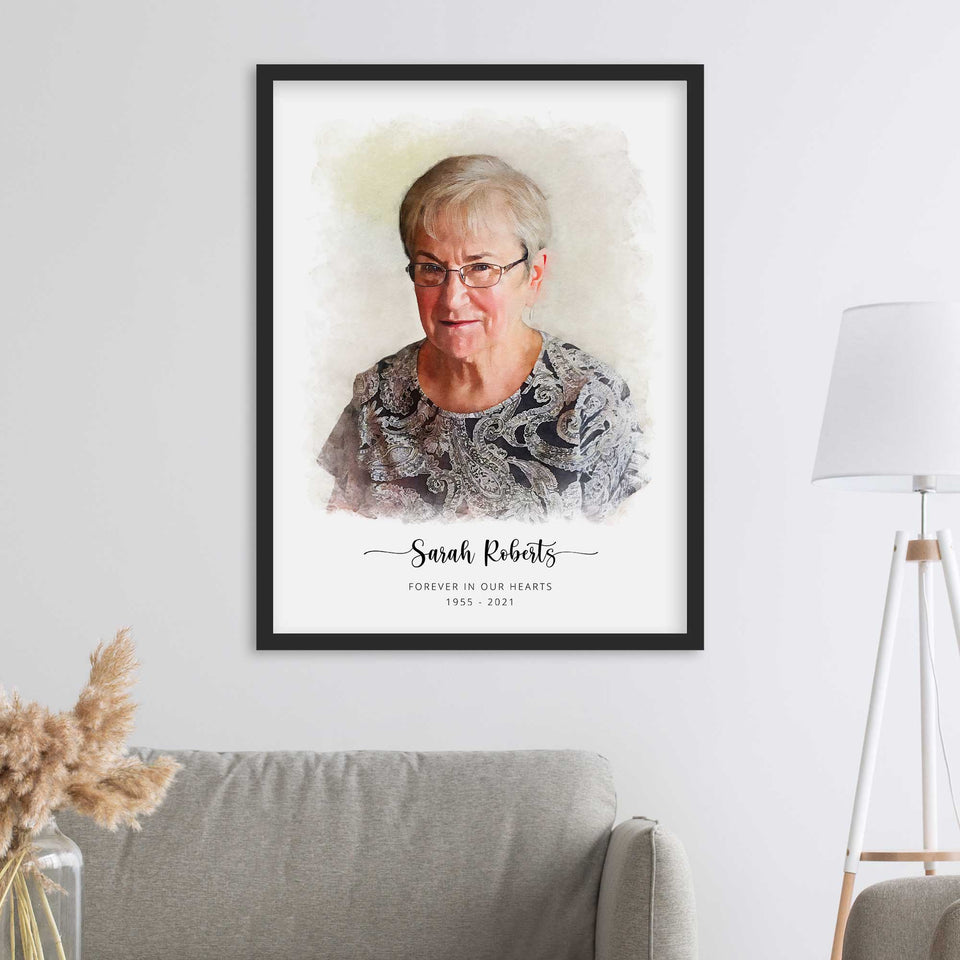 Watercolor-style memorial portrait of an older woman in glasses, framed in black above a sofa, with her name and dates below