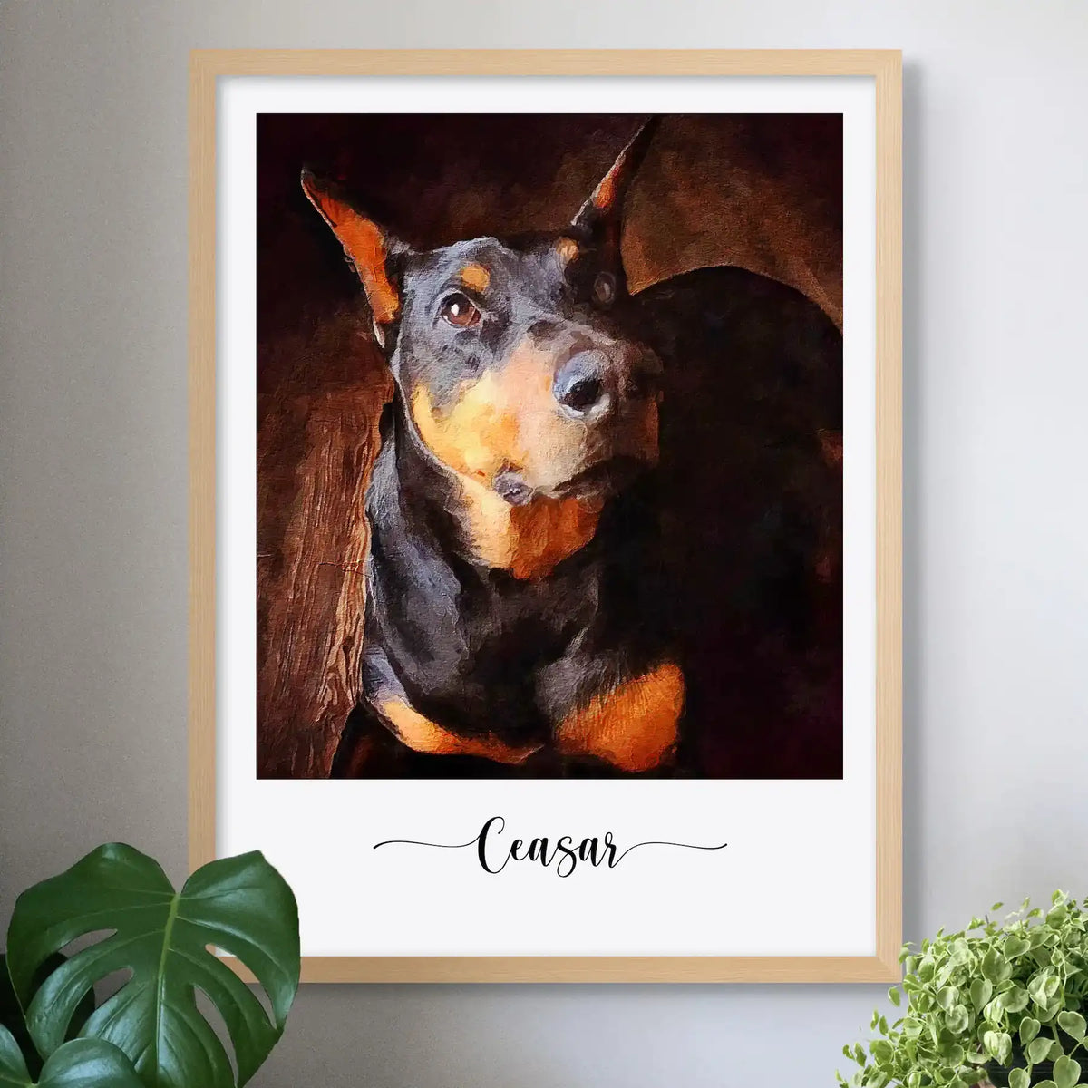 Oil-style portrait of a black and tan dog named Ceasar, in a light wood frame on a wall beside plants