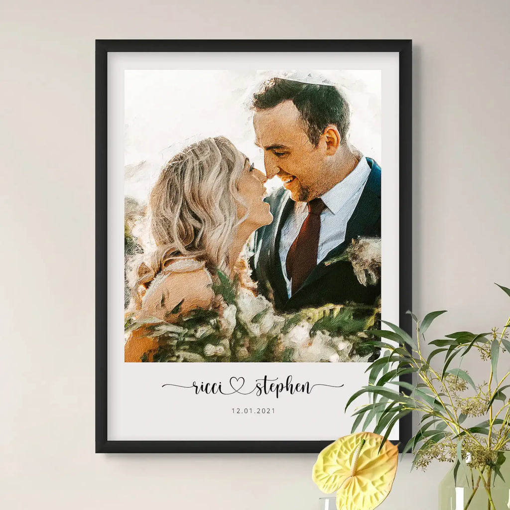 Oil-style portrait of a couple nose to nose, in a black frame on a wall beside a plant, their names and a date below