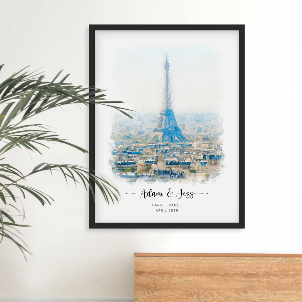 Watercolor-style portrait of the Eiffel Tower over Paris rooftops, framed in black, with names and a date beneath